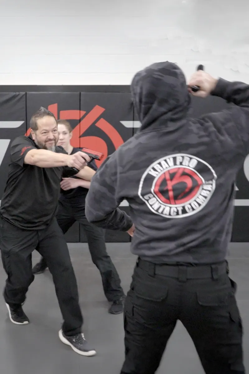 Krav Pro instructor demonstrating a self-defense movement with an adult Foundations student.