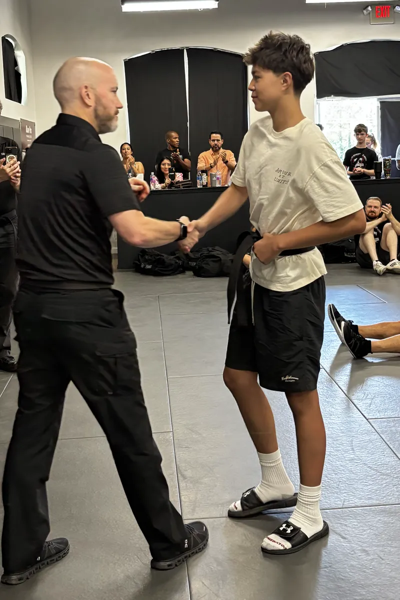 Adult Krav Pro students practicing a controlled partner drill with instructor guidance.