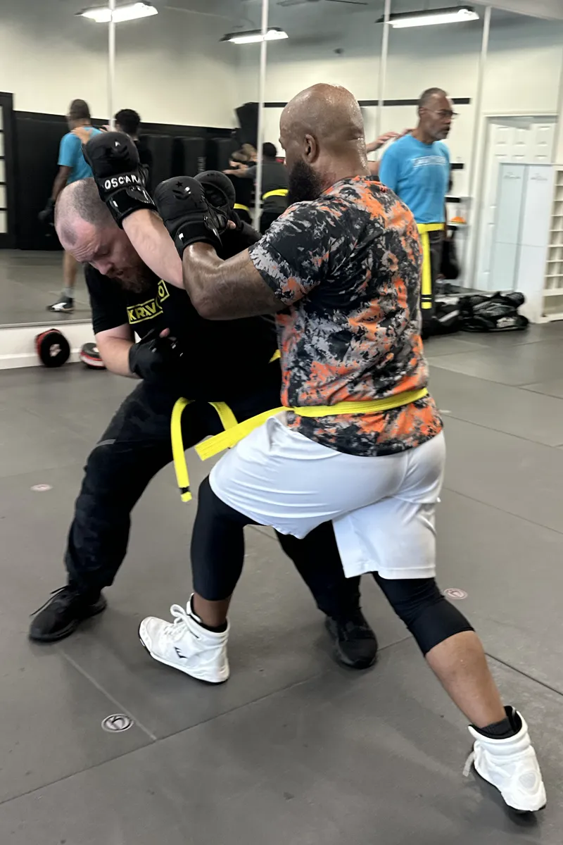 Adult Krav Pro students learning a controlled self-defense drill with instructor coaching.